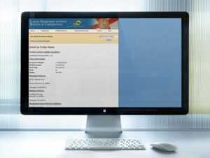 Desktop computer monitor on a white desk displaying a website with a blue header and a blue right panel; keyboard and mouse are in front.