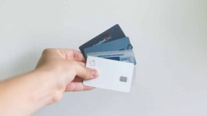 Hand holding four credit cards fanned out in a display by the fingers.